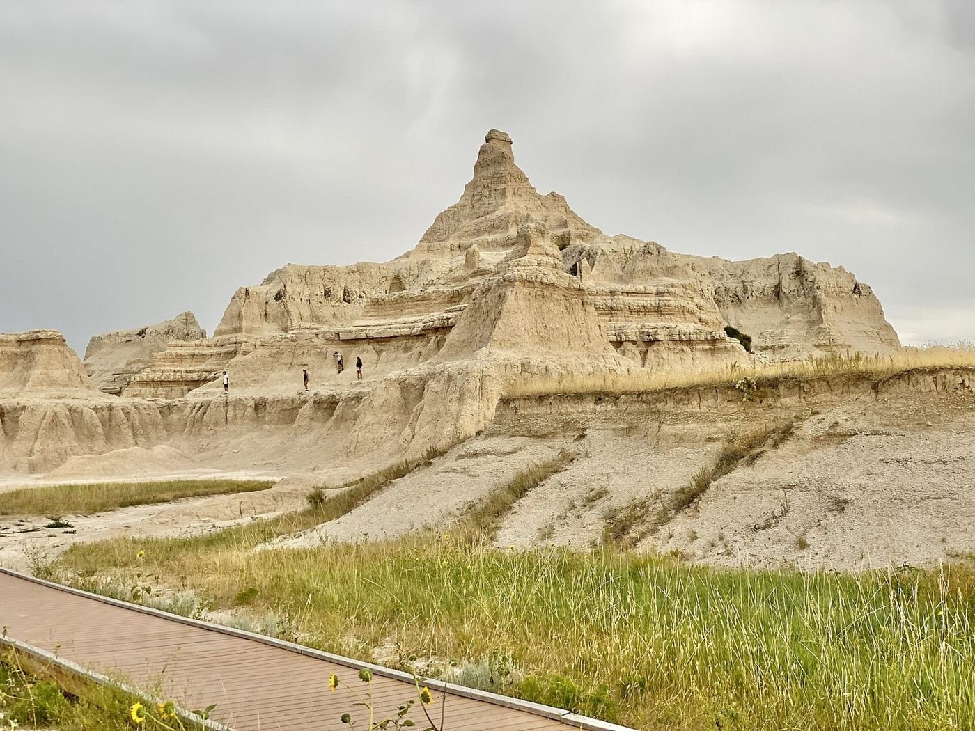 Eroded sandstone pinnacles above a boardwalk and prairie grass seen from the Notch and Door trails in Badlands National Park