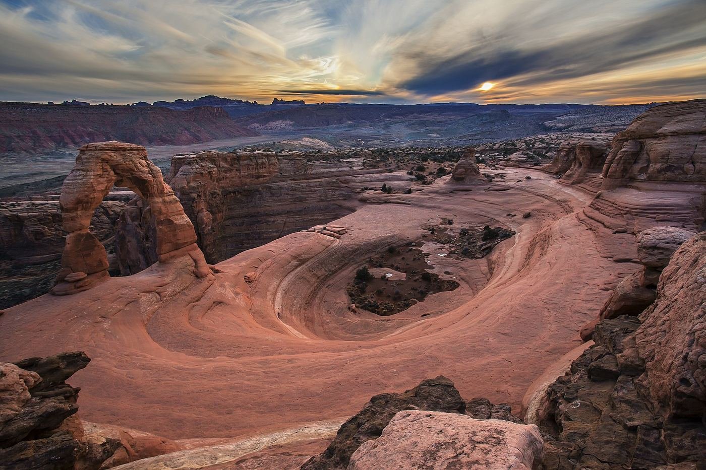 Delicate Arch glowing at sunset with the La Sal Mountains behind it